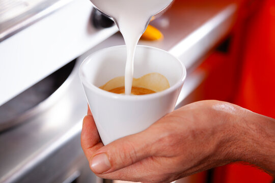 Filling a cup of coffee with milk at a caf&eacute;.