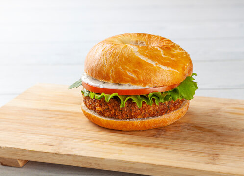 Delicious bagel with a veggie burger, tomato, and yogurt sauce.