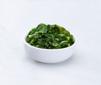 Bowl filled with cooked chard on a white background