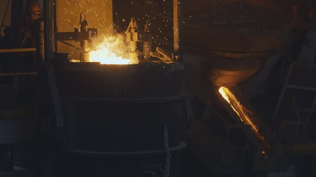 Metal production process in a metallurgical factory. Modern metallurgical factory. Red hot metal in a modern factory. Steelworks technology. Pouring liquid hot metal to shape. Sparks flying all around