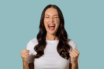 Overjoyed lady cheering, celebrating with clenched fists, posing with Italian painted flag on her...