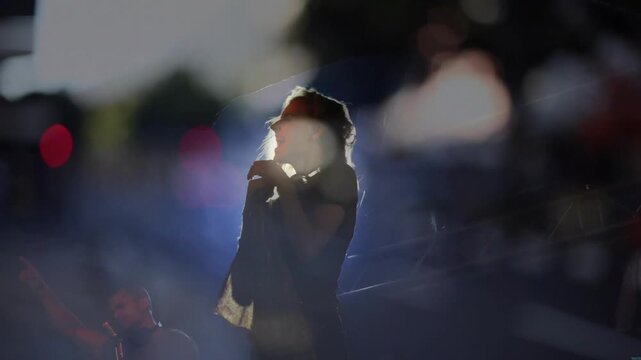 Lead singer head whipping flipping to settling hair singing lifting mic amid music flares haloing
