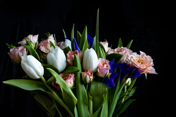 Fototapeta premium beautiful bouquet. pink roses, white tulips on a black background. Present. Surprise. Congratulations