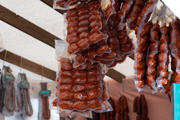 Ristras of spicy red chorizo sausages in vacuum packaging for sale at an outdoor food stall. Concept of traditional Spanish deli, cured meats, and food preservation.