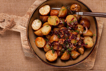 Savory roasted potatoes with herbs and caramelized onions served in a rustic bowl on a wooden board