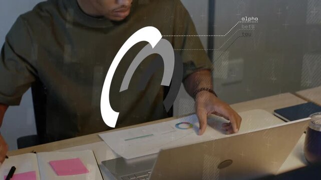 Man writing on notebook starting logo grid overlay while using laptop, reviewing design charts