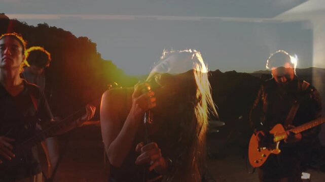 Singing lead singer gripping mic and whipping hair as riff starting at rehearsal, sunrise overlay