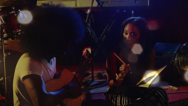 Guitarist starting tempo for music sync while drummer cueing from stand, bokeh obscuring them