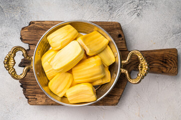 Sweet, golden jackfruit pods (bulbs) in a traditional metal bowl with a fork. Exotic tropical snack or dessert with copy space © Mironov