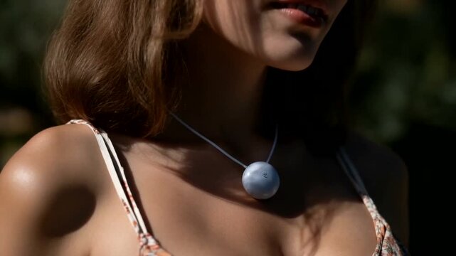 Woman wearing a pendant in a sunny outdoor setting