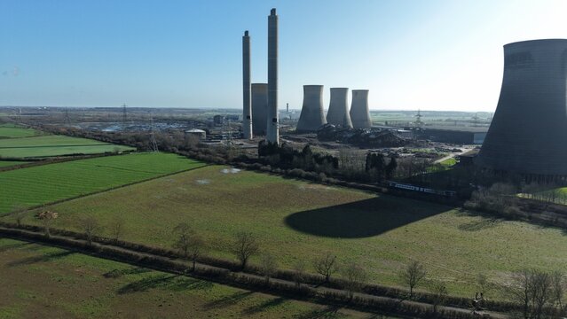 Aerial drone view of decommissioned West Burton power station cooling towers and chimneys under active demolition process in Nottinghamshire UK.