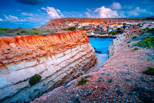 Malta popular Popeye Village at dawn, traditional wooden houses in turquoise bay.