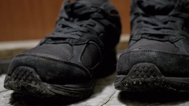 Close-up of dirty black sneakers, highlighting the dust and grime accumulated on the surface. Suitable for cleaning, repair, or lifestyle themes.