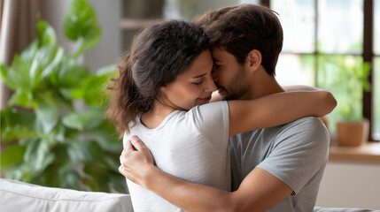 Fototapeta premium Unrecognizable couple embracing in a bright living room with a sofa, indoor plants, and soft natural light, relationship warmth, cozy home lifestyle concept, with copy space