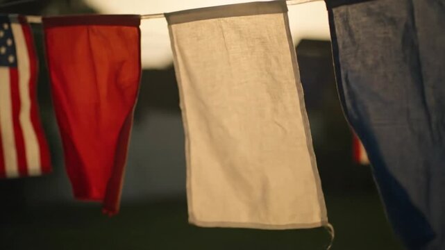 Close-up of assorted colored underwear hanging on a clothesline with an American flag in the background, blurred and dark surroundings.