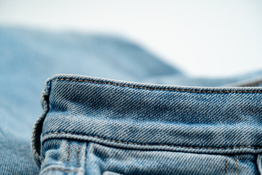 Close up of denim waistband edge with stitching and fabric texture.