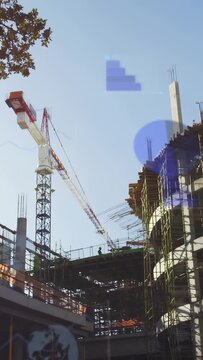 Vertical video: Construction crew moving on slab as HUD on cue drifting, tagging crane rebar for QA