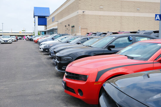 Retail parking lot outside the CarMax used cars dealership building with a row of parked vehicles.