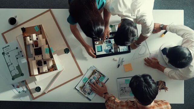 Time lapse of designer looking at model while discussing about building. Top view of architect engineer explaining idea while talking and writing blue print scattering at meeting table. Alimentation.