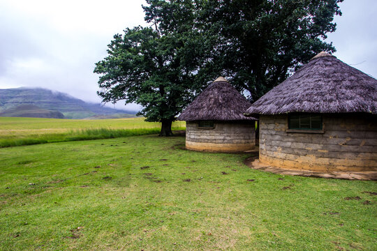 Traditional thatched huts at Winterhoek, one of the overnight stops on the Giants Cup hiking trail in the Drakensberg mountains of South Africa, with mist shrouding the mountains in the background.