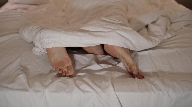 A view of the legs of a man and a woman in bed, a man on top, but he quickly finishes, gets off and falls asleep