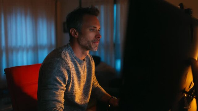 Man looking at a computer screen displaying many small video call windows at night