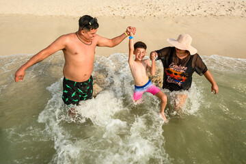 Happy parents playing with their young son in the ocean waves on a Mexican beach © alejandro