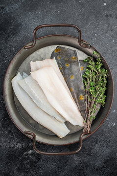 Raw flounder flatfish fillets with skin and thyme on metal tray on dark background fresh seafood ingredient