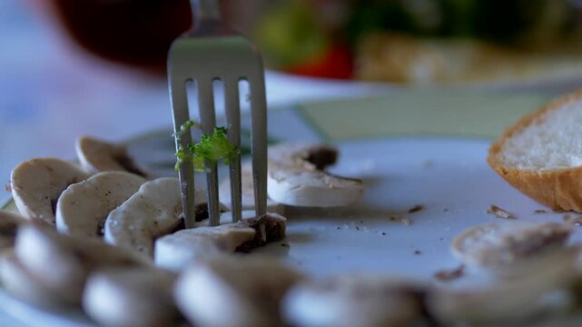Fork Lifting Marinated Mushroom Slice Above Plate at Dining Table &mdash; Agaricus bisporus, Mushroom Appetizer, Food Close-Up, Home Cooking Concept