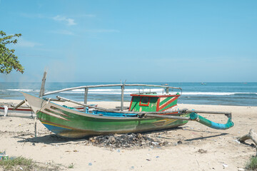 Fototapeta premium Traditional Colorful Outrigger Fishing Boat on the Sandy Shore of Sawarna Beach, Indonesia