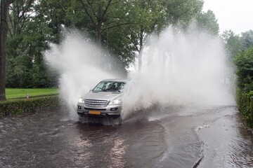 Fototapeta premium Car driving through a flooded street in the Netherlands