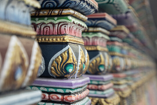 A close-up, perspective view of the ornate Dravidian pillars at the Sri Maha Mariamman Temple. These stacked structures feature intricate South Indian moldings and decorative bands, most notably a vib