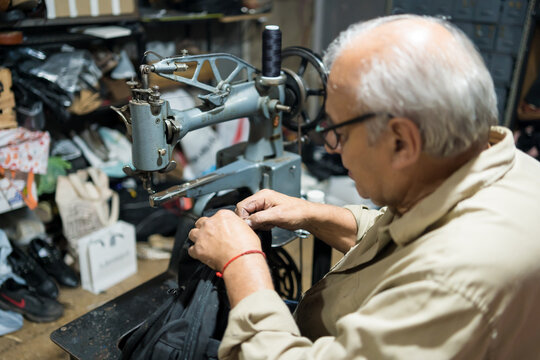 Latino upholsterer meticulously repairs a backpack using a vintage industrial sewing machine