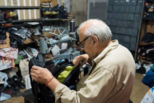 Latino upholsterer meticulously repairs a backpack using a heavy-duty industrial sewing machine