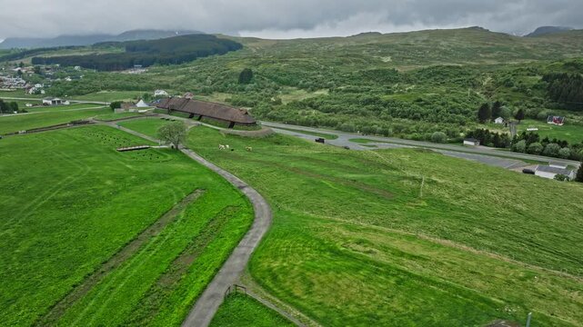 Drone aerial panorama of Lofotr Viking Museum and Viking longhouse in Borg, Lofoten Islands, Norway. Historic Norse site set within rolling green landscape of northern Norway.