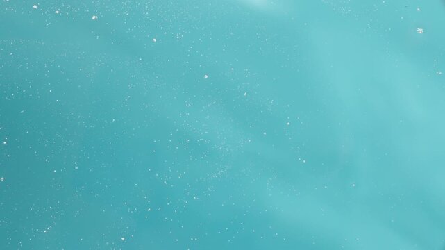 View from below, from under the glass on a blue background. Water bubbles and a man's hand wiping it with a cloth. Close-up of cleaning under the glass.