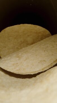 Vertical video. Saddle-shaped chips neatly arranged on the table, the camera zooms into their can, and I take one piece. Dolly slider, close up.