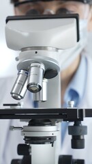 Fototapeta premium Scientist wearing lab coat and protective glasses using a modern microscope in a laboratory setting, conducting research and experiments in a scientific environment. Health care and science concept