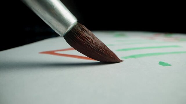 First-person view, macro shots of the artist's brush, painting with red paint on a black background.