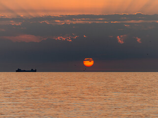 Obraz premium Merchant ship during sunrise over the Mediterranean Sea seen from the beach in Torremolinos. Costa del Sol, Spain