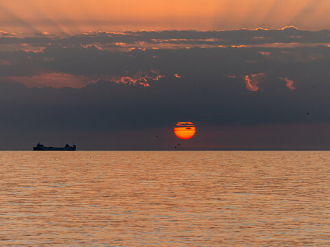 Merchant ship during sunrise over the Mediterranean Sea seen from the beach in Torremolinos. Costa del Sol, Spain