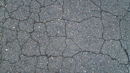 Obraz premium Close-up of cracked asphalt pavement texture