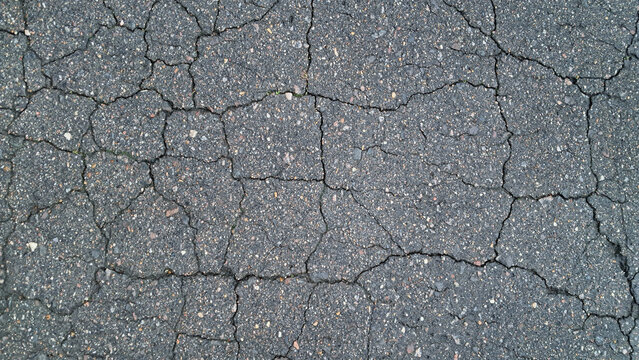 Close-up of cracked asphalt pavement texture