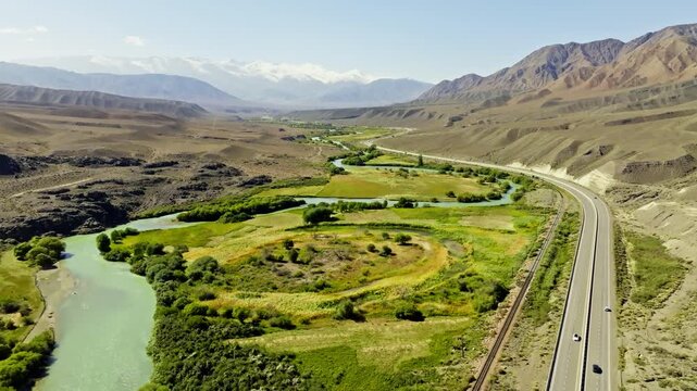 Aerial view captures vast Chu river winding through mountains in Kyrgyzstan. Dolly backward camera movement.