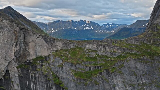 Drone aerial of mountain cliffs and fjord landscape near Segla on Senja Island, Norway. Arctic alpine scenery with rocky ridges and dramatic northern coastline.