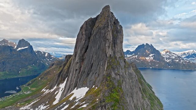 Aerial view of Segla mountain peak on Senja Island, Norway. Dramatic Arctic landscape with steep rocky summit rising above the fjord and surrounding alpine peaks.