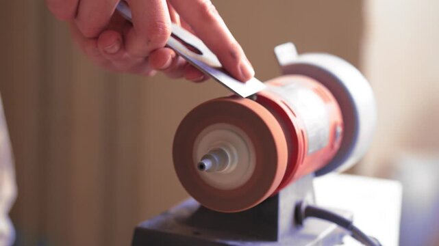 Sharpening Metal Tool on Grinding Wheel with Bright Flying Sparks in Workshop
