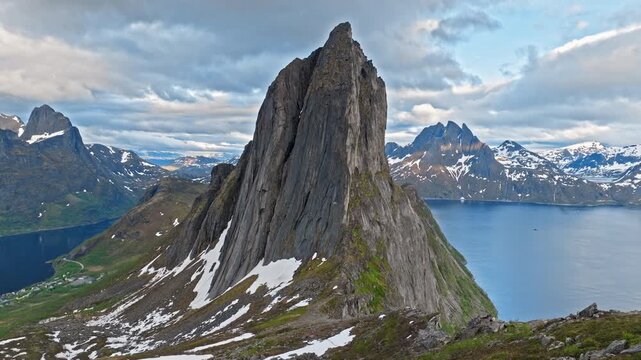 Drone aerial approaching the famous Segla mountain peak on Senja Island, Norway. Dramatic Norwegian landscape with sharp summit above fjord and alpine terrain.