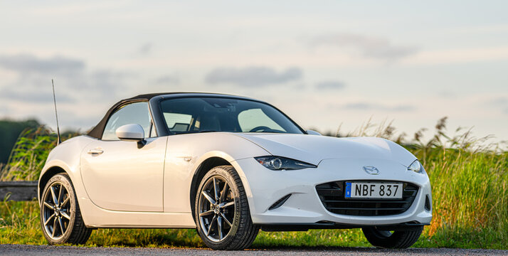 Gothenburg, Sweden - July 25 2024: White Mazda Miata convertible parked roadside at sunset landscape.