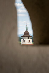 Baroque bell tower framed through stone window with countryside